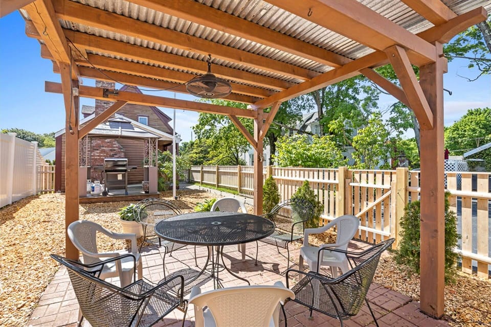 Beautiful covered outdoor setting area with 8 chairs, BBQ grill is also in a covered area