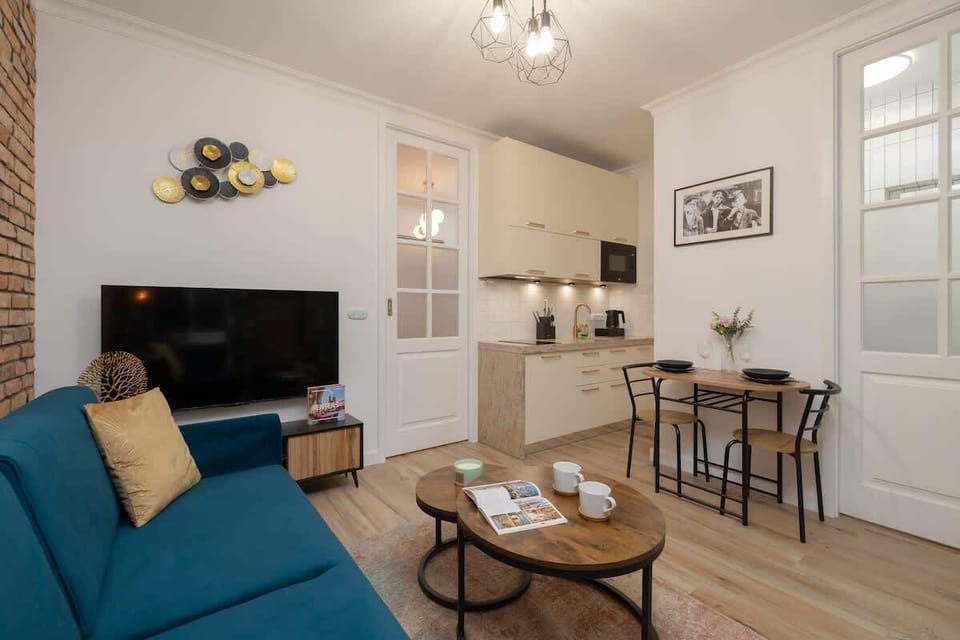 The living space blends modern elegance with home-like comfort – the sofa, TV, and dining table complete the cosy atmosphere.