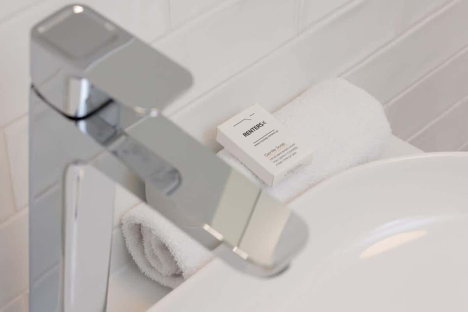 A close-up of a modern faucet with a mini soap bar set on the sink edge.