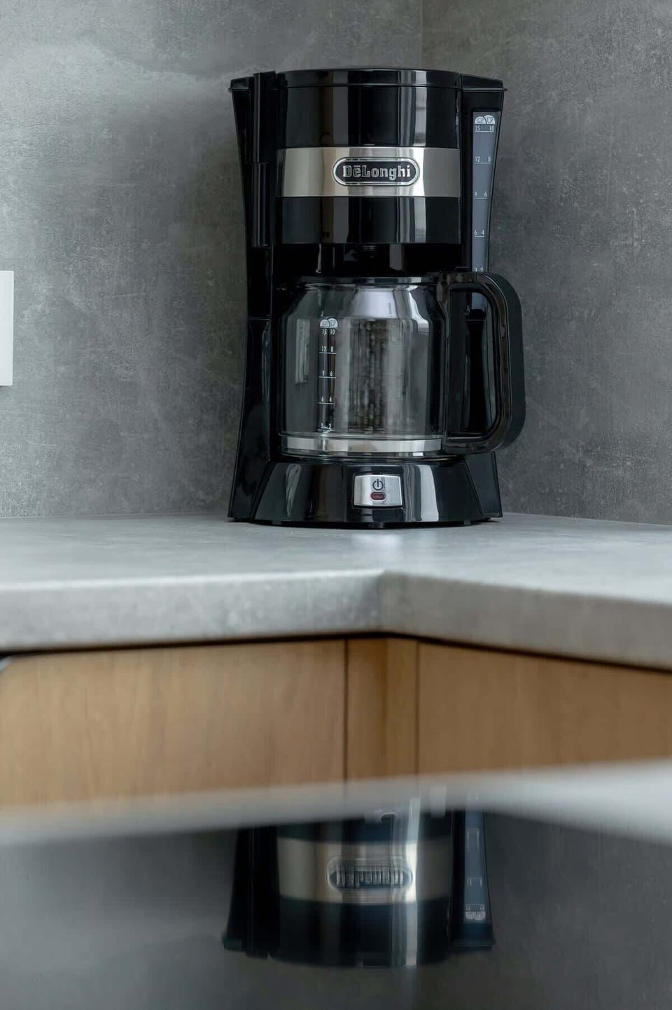 A close-up of a black coffee maker on the gray kitchen countertop, adding to the apartment’s convenience.

