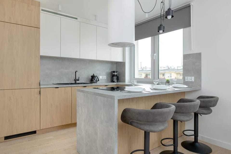 A well-organized kitchen with a built-in oven, light wood cabinetry, and a stylish breakfast bar with stools.

