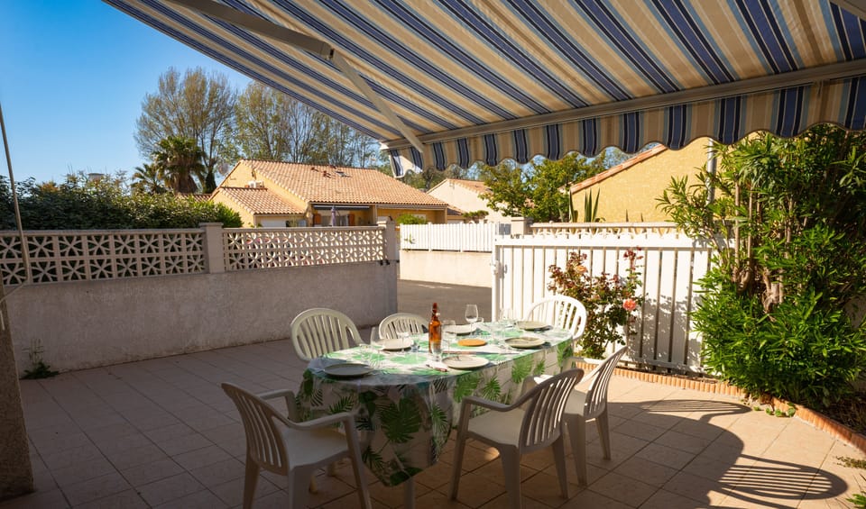 Terrace with garden furniture, charcoal barbecue and awning