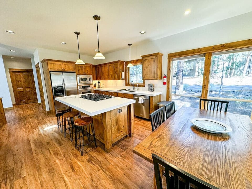 This open-concept kitchen is the heart of the home, with modern appliances, ample counter space, and large windows showcasing the tranquil forest views. Perfect for cooking and gathering