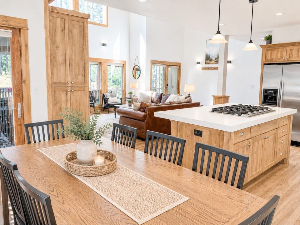 Prepare meals in this fully equipped kitchen featuring stainless steel appliances, a spacious island, and scenic views of the living area and towering pines