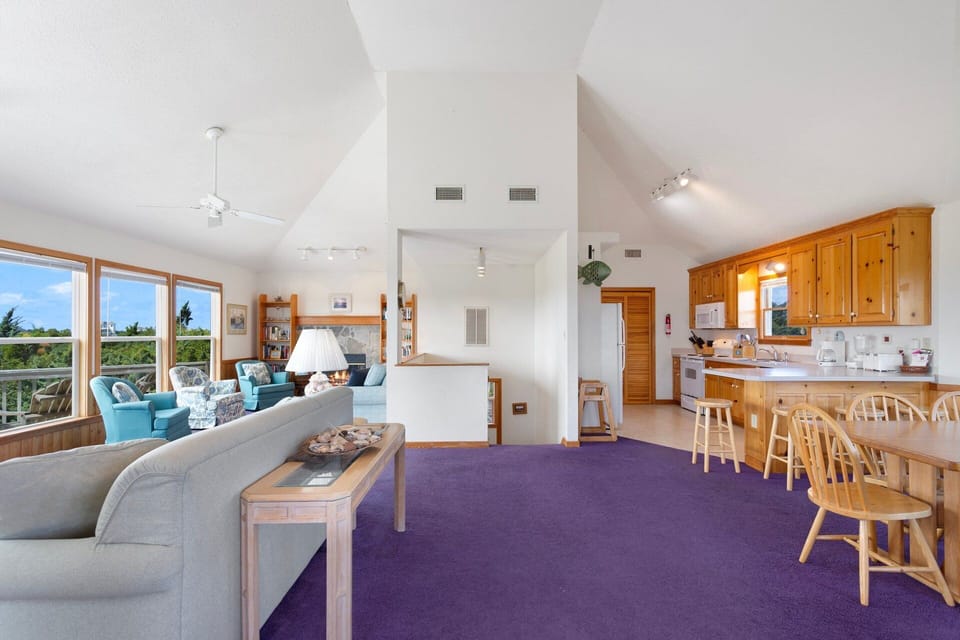 Living Area: Bright and airy Living Area with vaulted ceilings, cozy seating, and a wall of windows.
