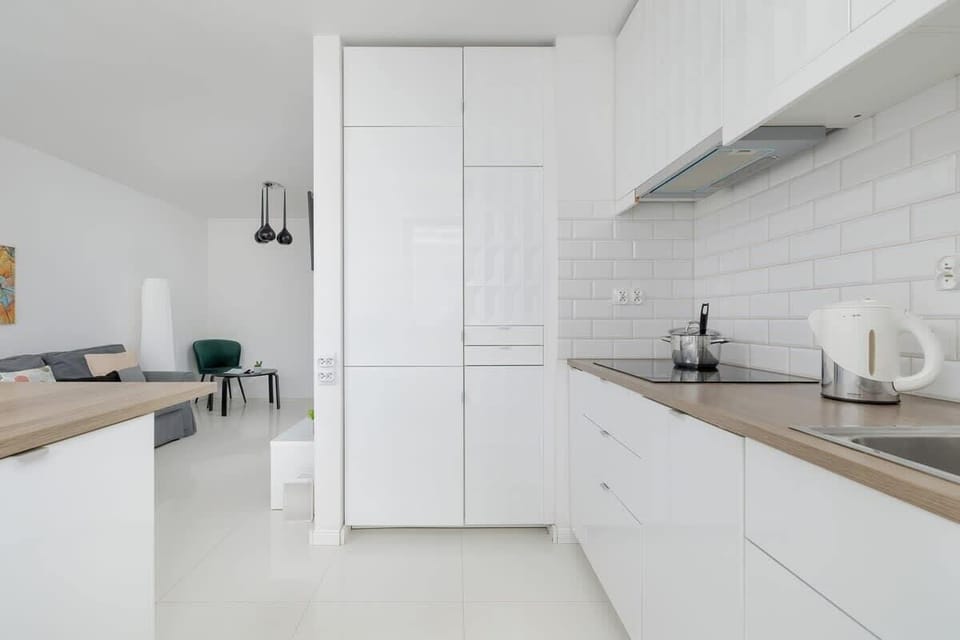 A modern kitchen with a wooden breakfast bar, black pendant lights, and stylish bar stools, blending functionality with elegance.

