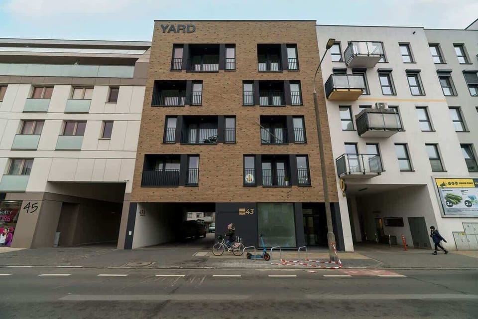 A view of the building’s exterior, showing multiple balconies and a modern, geometric design with contrasting materials and colors.