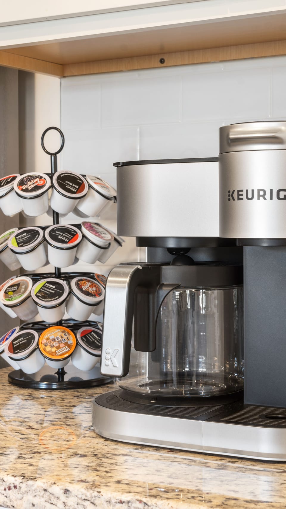 A sleek Keurig coffee maker beside a carousel of coffee pods.