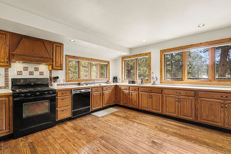 Your spacious kitchen features warm wood cabinets, modern appliances, and large windows overlooking peaceful trees.