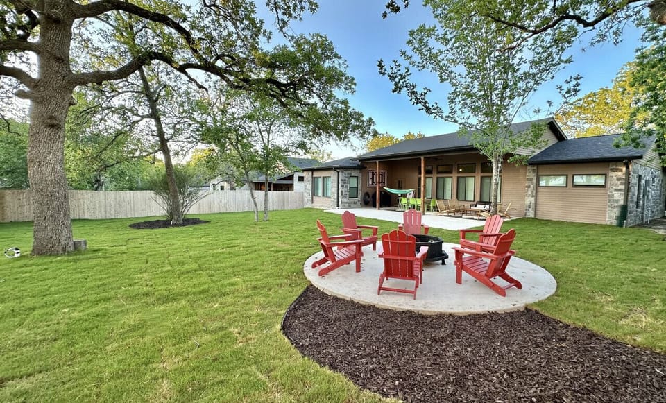 The backyard is a cozy retreat, boasting comfortable red lounge chairs encircling a crackling fire pit.