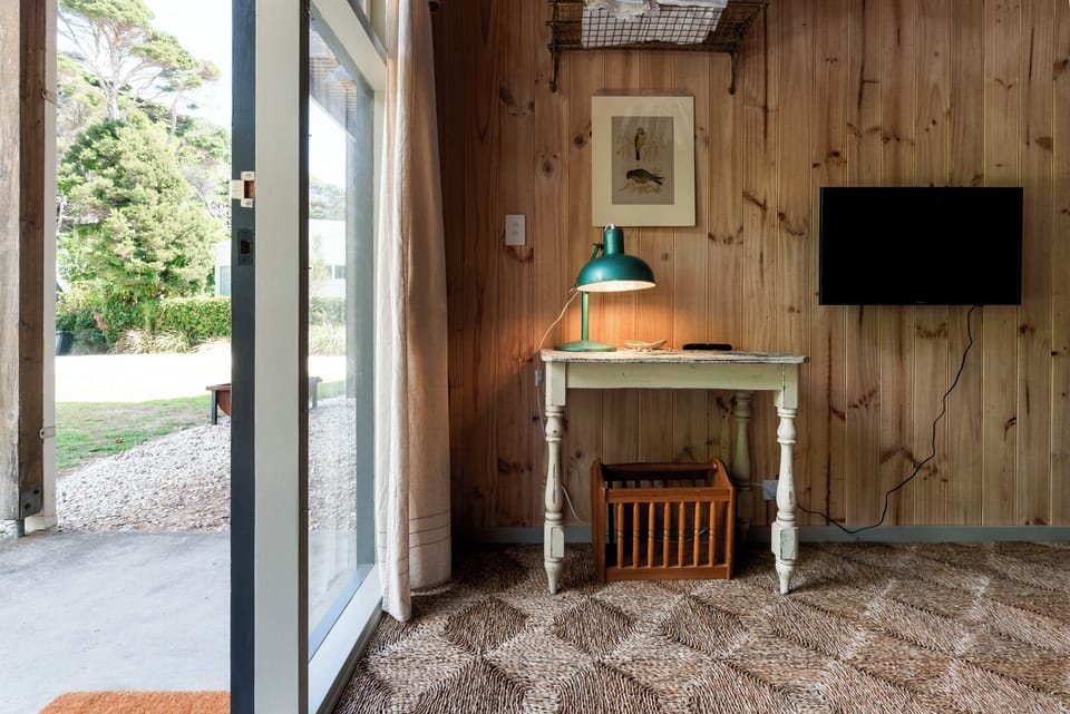 Cozy wood-paneled study nook with a small desk, green lamp, and patio access.