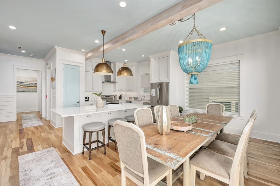 Your bright open-plan kitchen flows seamlessly into the dining space, where warm wood floors and stunning turquoise chandelier create the perfect gathering spot.