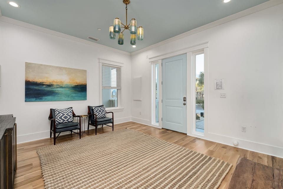 Relax in your stylish entry space, where coastal artwork and mid-century chairs create the perfect first impression.