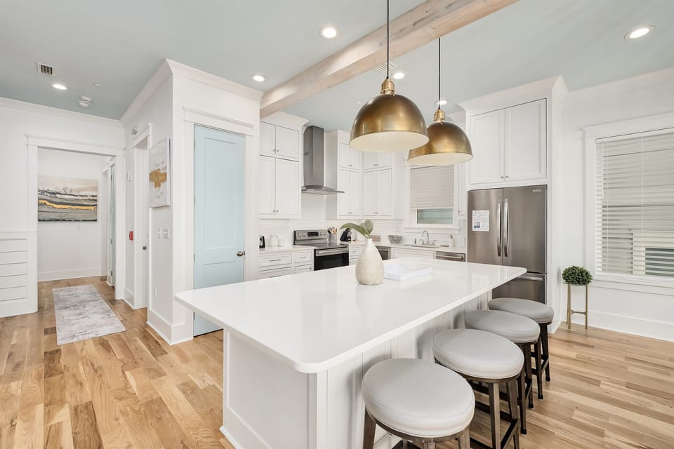 Your dream kitchen awaits with gleaming white cabinets, marble island, and brass pendant lights creating the perfect space for culinary adventures.