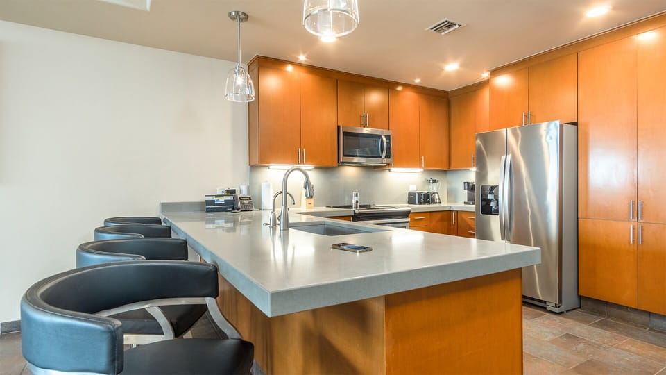 The kitchen counter is rimmed with upholstered chairs.