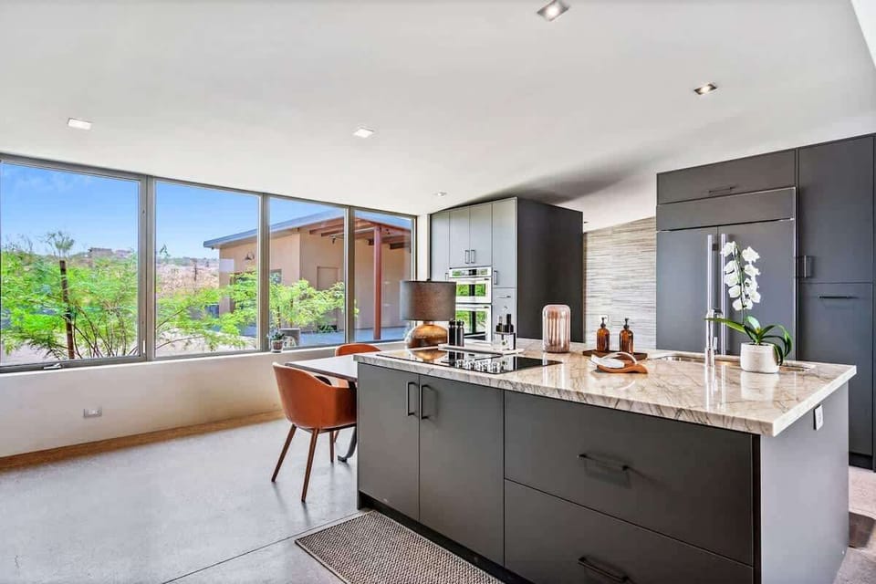 Estate 1: Fully equipped luxury kitchen stocked with all culinary essentials and features high-end stainless-steel appliances, a kitchen island, a breakfast table, and a wet bar / coffee station.