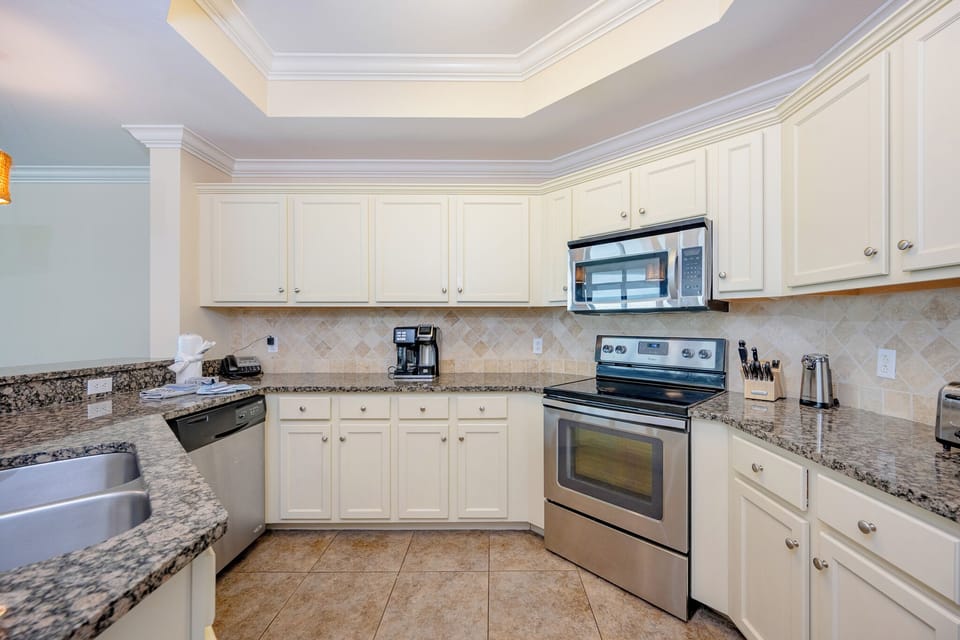 The kitchen features granite countertops, stainless appliances, and a modern coffee maker, perfect for starting to your day