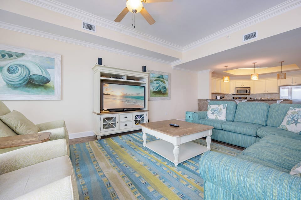 This inviting living area features a teal sectional sofa, a stylish coffee table, and a view into the modern kitchen