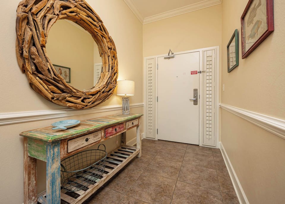 This welcoming entryway features a rustic wooden mirror, colorful console table, and soft lighting for a warm ambiance