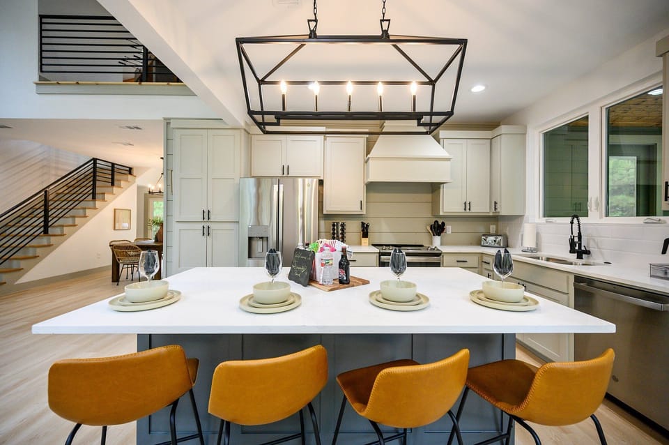 Sophisticated kitchen w/ island, stainless steel appliances, & stylish lighting.