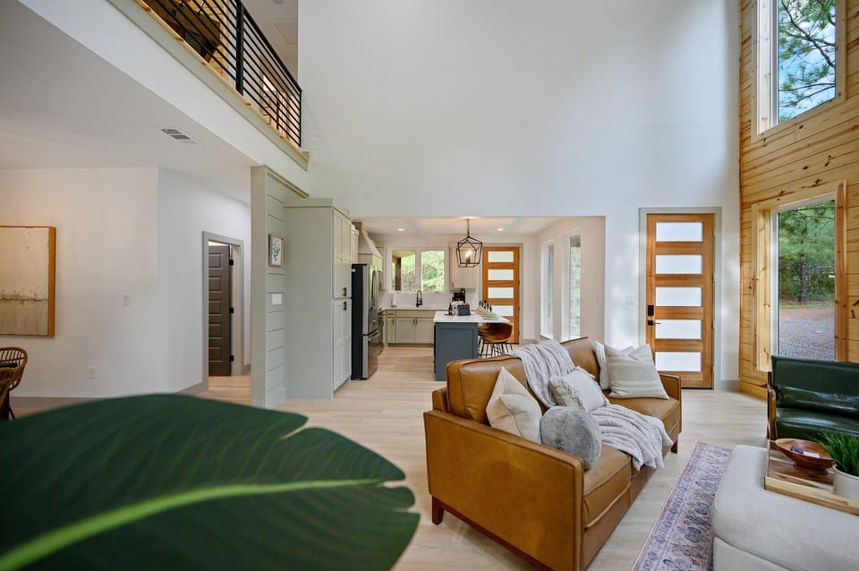 Elegant open living room with high ceilings, cozy seats, and sunlight.