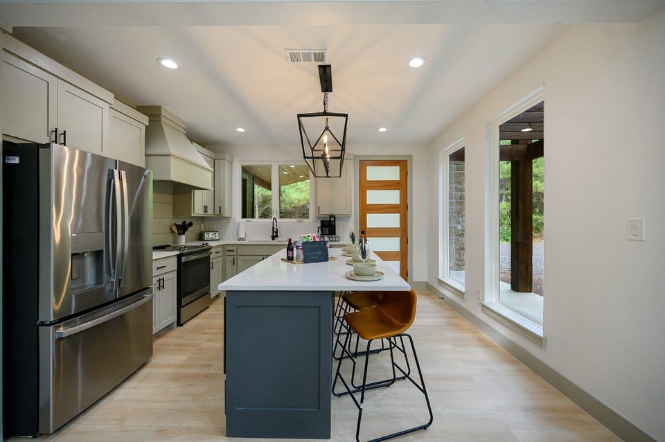 Sleek kitchen with stainless steel appliances, island, and large windows.
