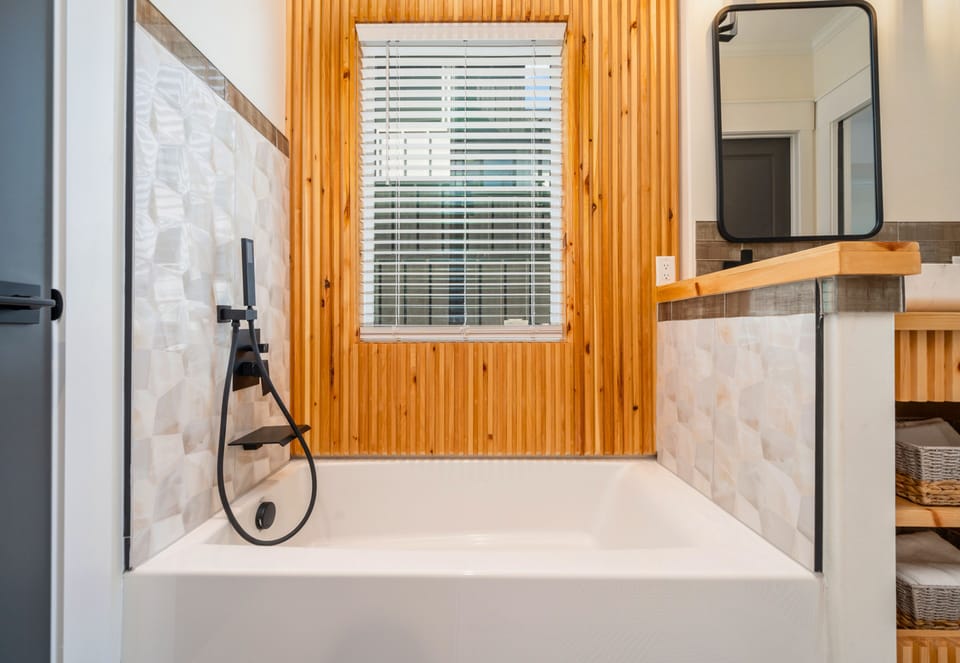 A soaking tub positioned beneath natural wood details creates the perfect setting for a relaxing evening.