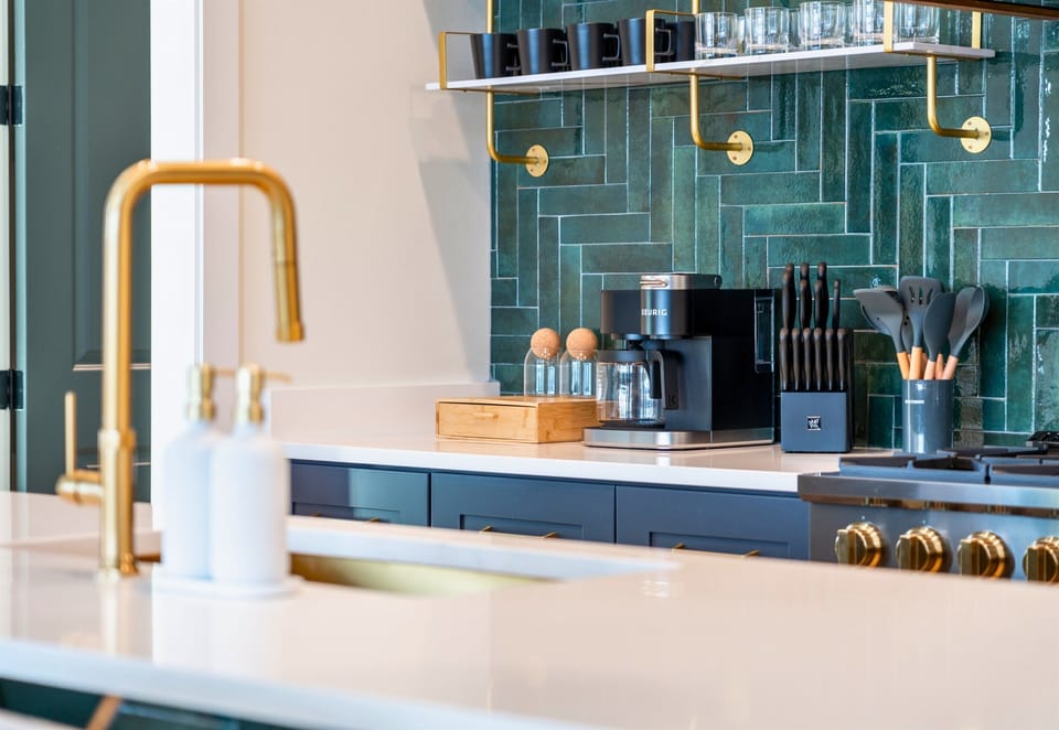 A Modern Style Kitchen With Gold Fixtures And A Stylish Backsplash.
