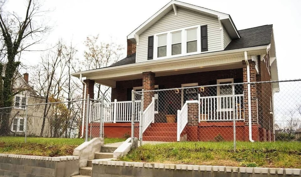 An inviting home with a charming chain link fence, steps leading to the front door. Nestled in a downtown location, this residence offers both convenience and allure—a perfect blend of urban living and cozy comfort.