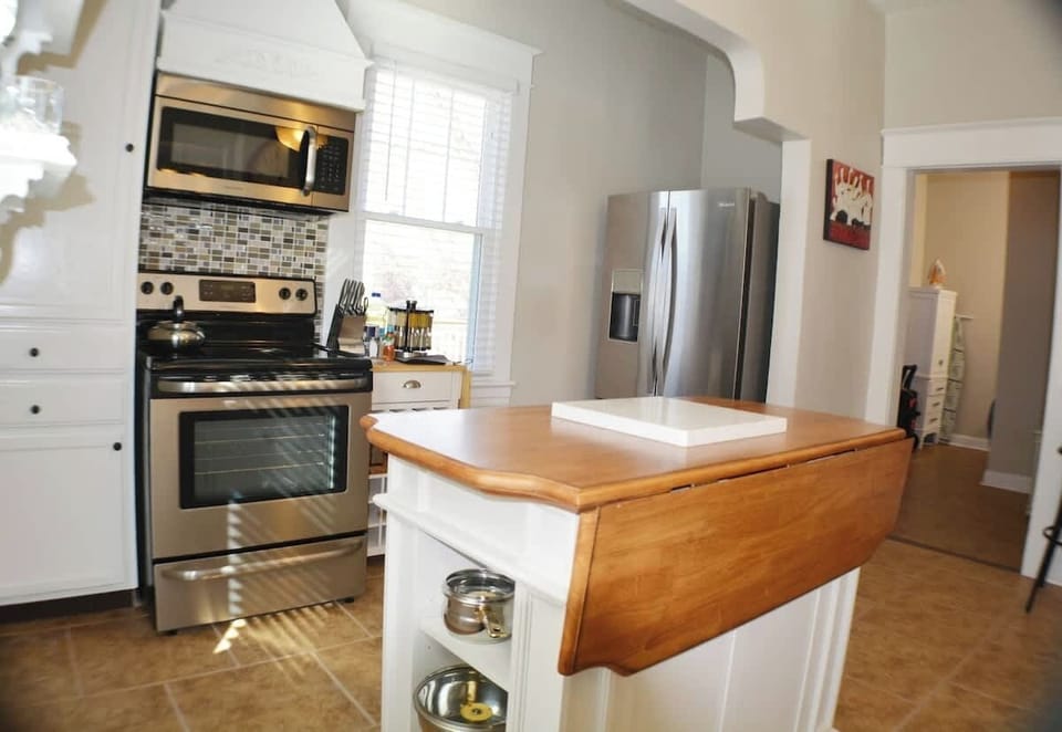 Experience culinary luxury in this modern kitchen—stainless steel appliances and a wood countertop adorned with a stylish wooden cutting board. Full kitchen amenities converge seamlessly, creating a space where functionality meets elegance
