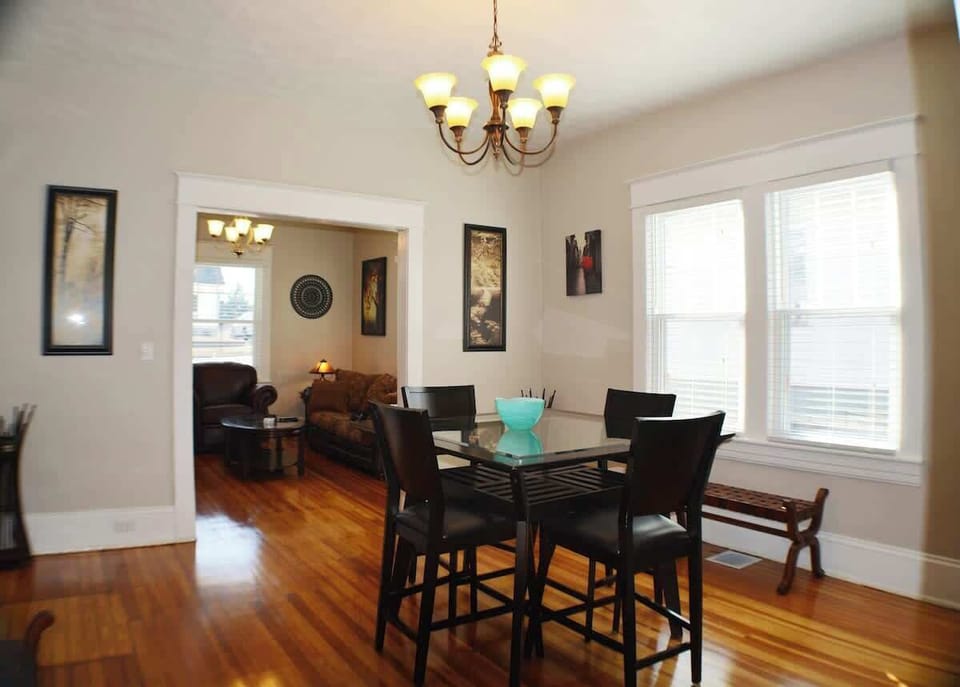 An elegant dining haven—hardwood floors, a captivating table, and chairs beneath a radiant chandelier. This room enchants with its charming ambiance, turning every dining experience into a moment of sophistication in your elegant and inviting home.