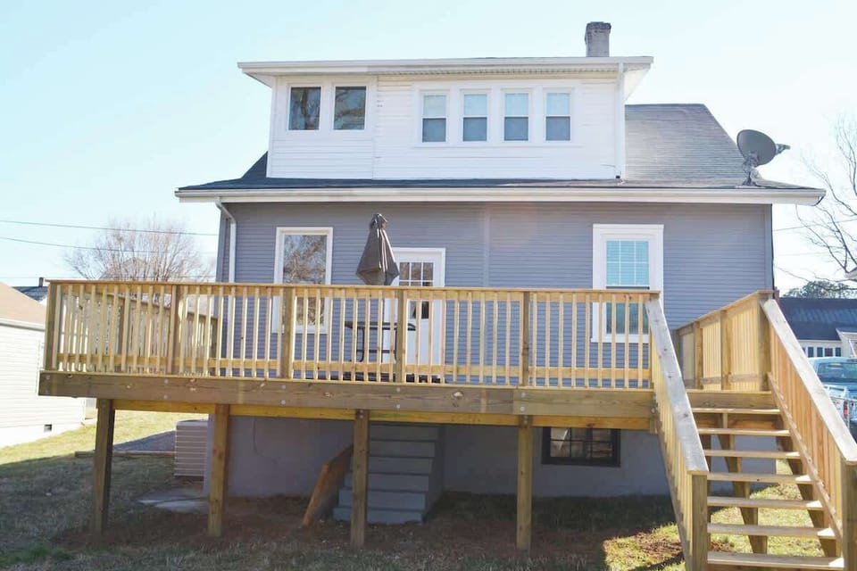 Elegance unfolds in this charming home, where a welcoming deck complements stairs leading to the front door. 