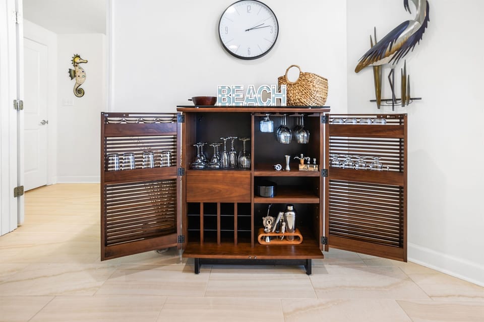 Your stylish bar cabinet awaits, stocked with glassware and coastal charm for memorable evenings together.