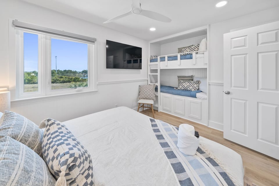Unwind in your bright bedroom featuring built-in bunks and coastal views through large windows.