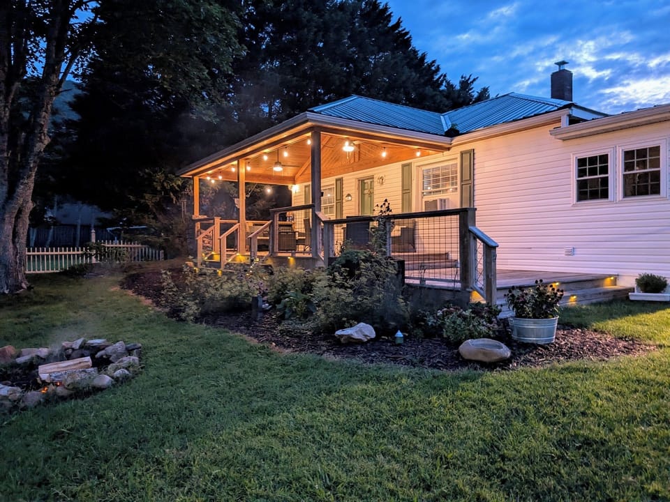 The Bailey Hot Springs — covered porch at dusk with fire in fire pit and Blue Ridge mountain views