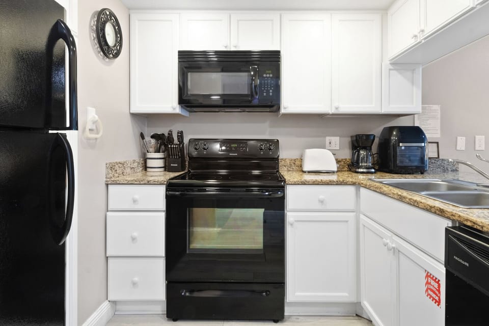 A fully equipped kitchen with sleek black-accented appliances, blending style and functionality for your cooking needs.