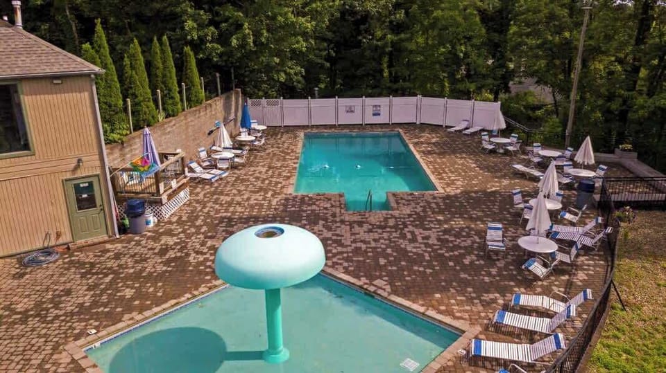 Relaxing Oasis: Dive into fun at our sparkling seasonal pool surrounded by lush greenery and lounge chairs!