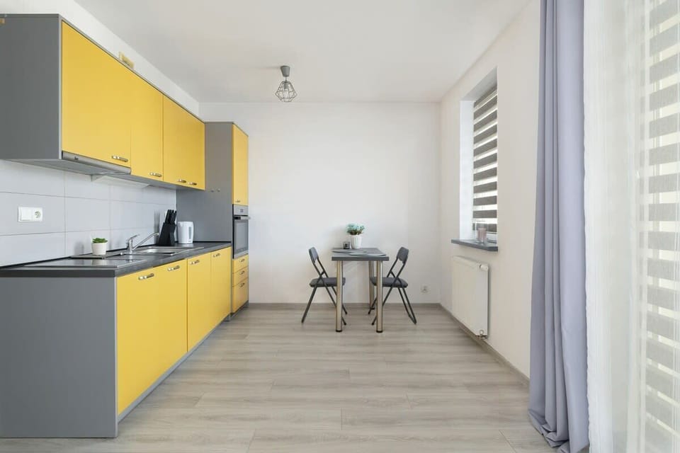 A dining area within the kitchen, featuring a small table with two chairs and large windows for natural light.

