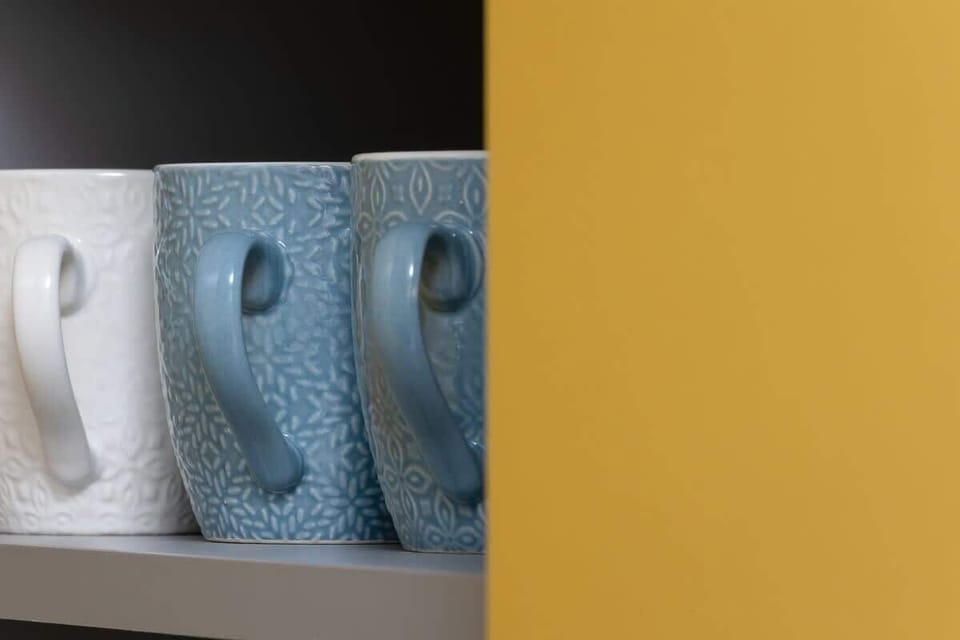 A close-up of blue ceramic mugs neatly arranged in a cabinet, adding a pop of color.

