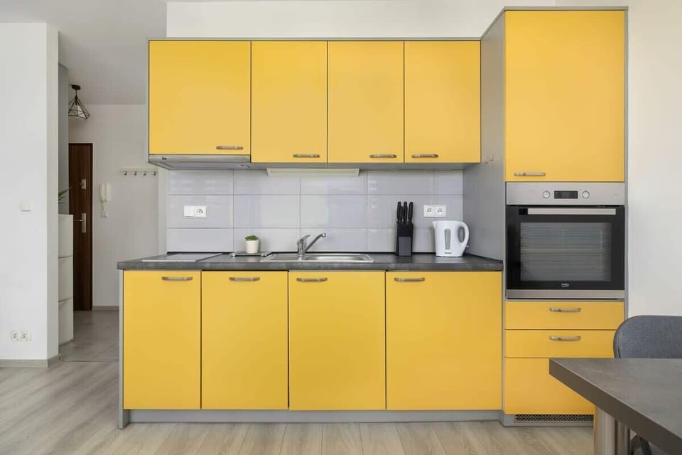 A kitchen with vibrant yellow cabinets, gray countertops, and modern appliances, adding a stylish contrast.

