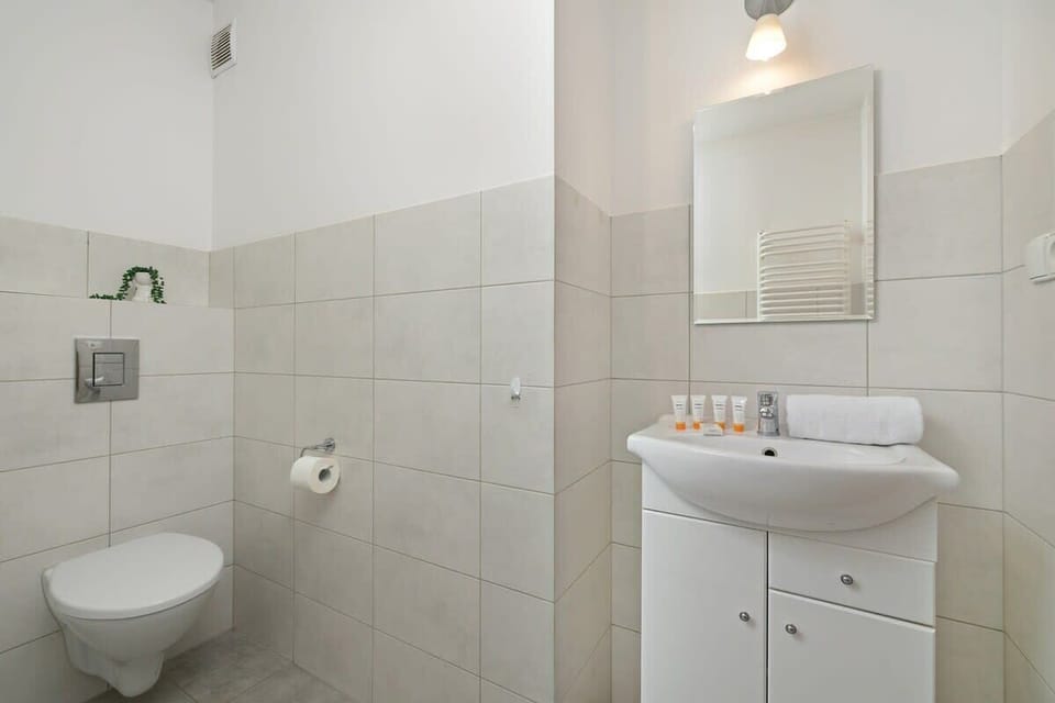 Another view of the bathroom, featuring a sink, mirror, and soft lighting creating a clean and functional space.

