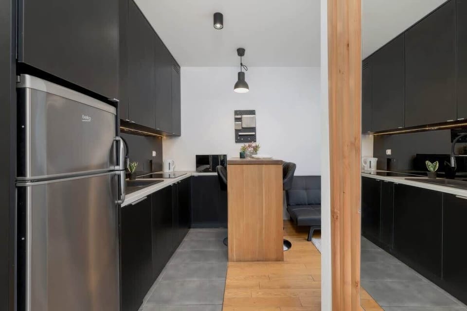 A sleek kitchen with black cabinetry, wooden countertops, and a modern, open layout.

