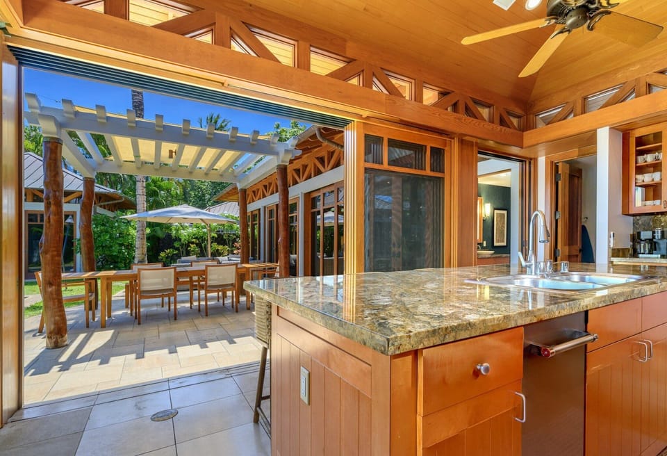 The island bar overlooking the outdoor lanai with umbrellas for a fun meal prep..