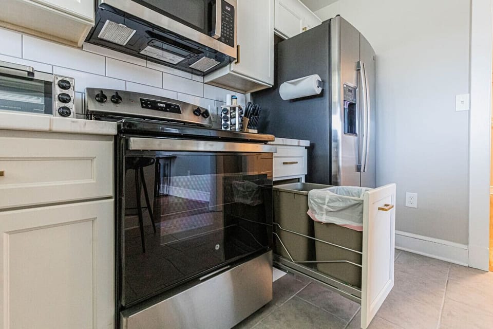 Effortlessly maintain a tidy space with our convenient hideaway trash can discreetly nestled within a cabinet, maximizing both functionality and aesthetic appeal in the kitchen.