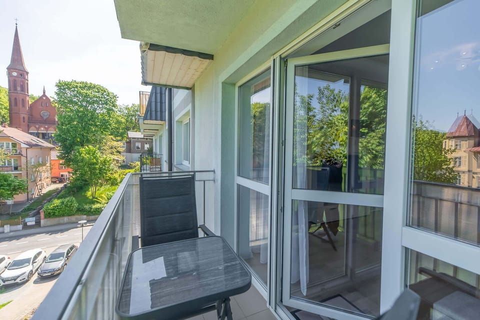 A repeated view of the balcony with the same table and chairs, once again showing a pleasant green landscape beyond the railing.