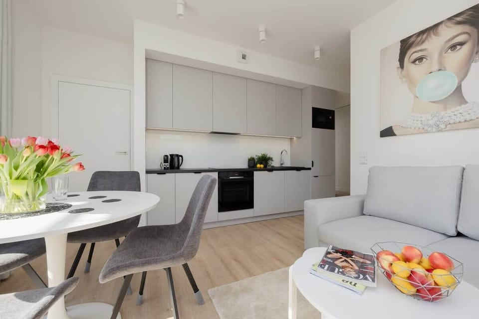 An open-plan kitchen and dining space connected to a cozy living area with floral wall decor.


