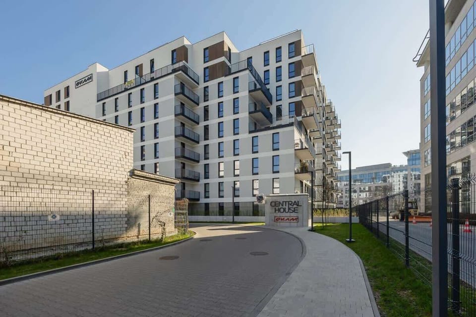 A modern residential building with multiple balconies, set against a clear sky.


