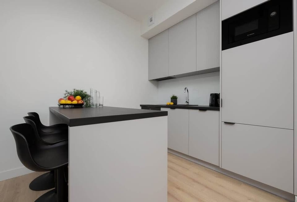 A compact yet stylish kitchen with white and black cabinetry, modern appliances, and a minimalist design.

