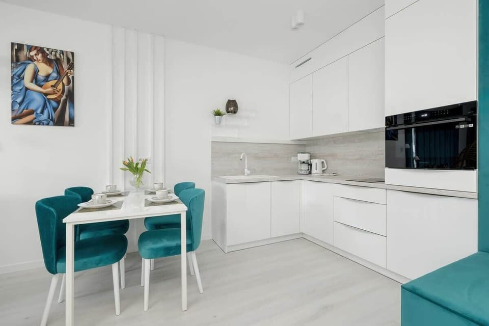 A stylish dining area with a turquoise table set, modern lighting, and decorative wall art.

