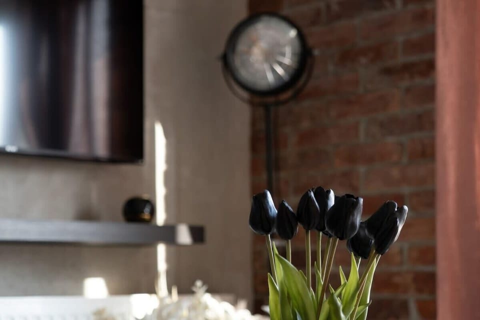 A close-up of a stylish interior decor piece, featuring black tulips, candles, and a rustic brick wall, adding warmth and character to the space.






